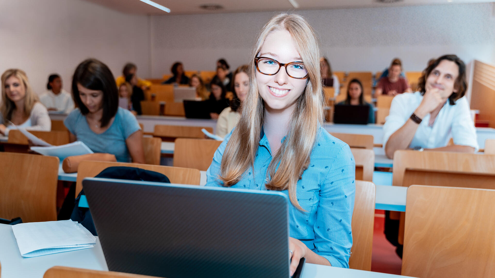 Studierende sitzt im Hörsaal vor einem Laptop