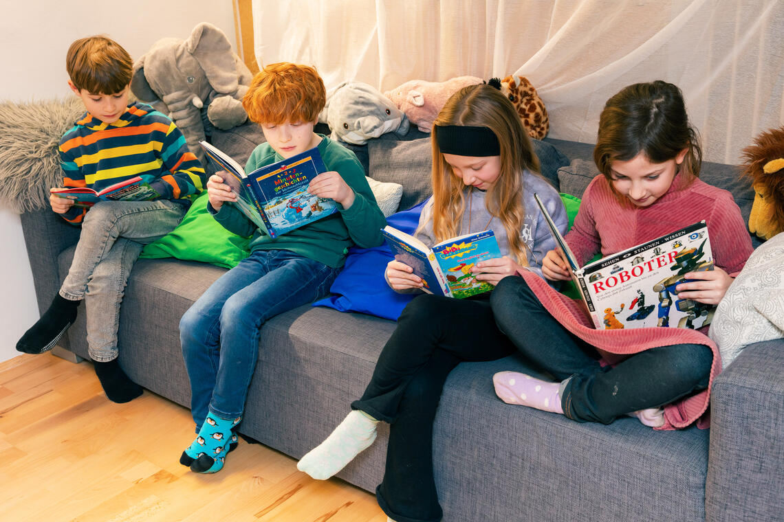 Kinder sitzen auf einem Sofa und lesen