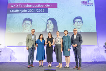 Viktoria Pauritsch mit Preis, Daniela Longhino, VR Elisabeth Amtmann und Vertreter WKO auf der Bühne, im Hintergrund Leinwand 