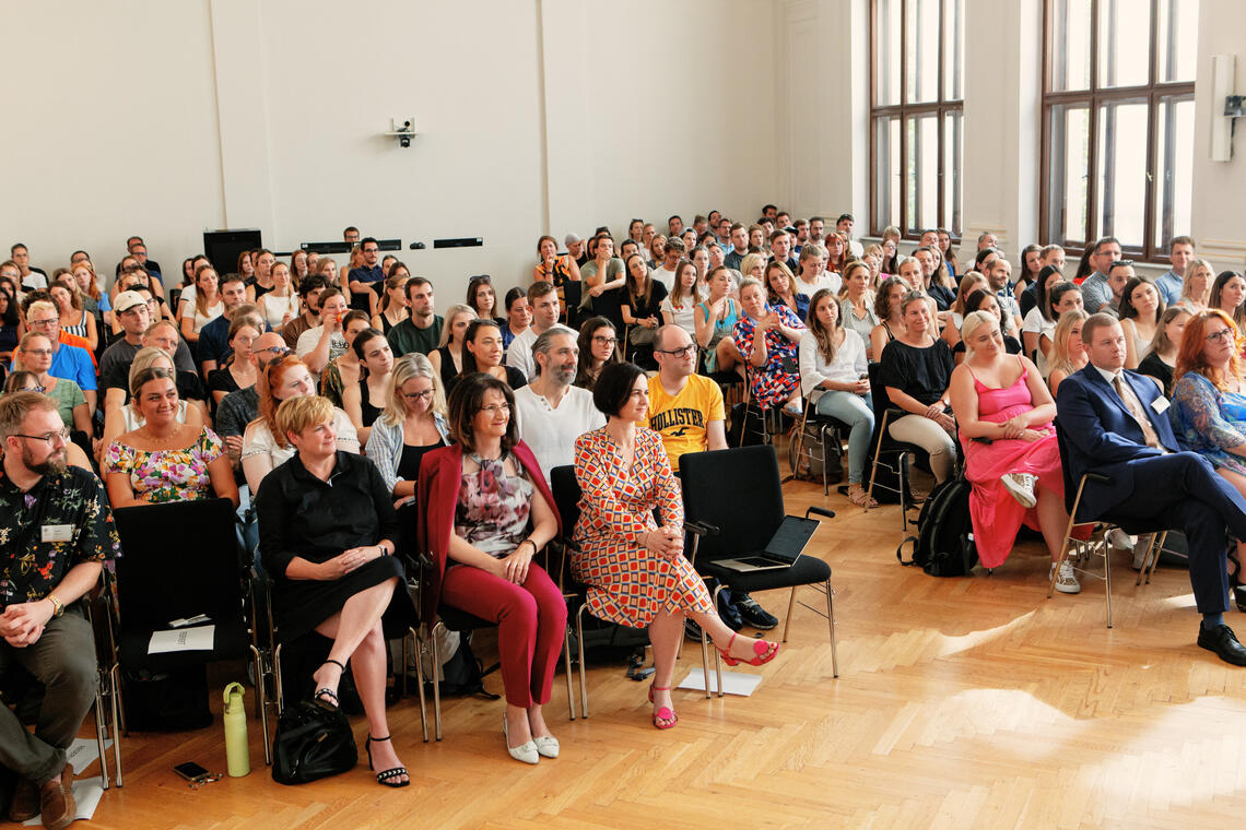 Berufseinsteiger*innen und Vortragende sitzen in der Aula 