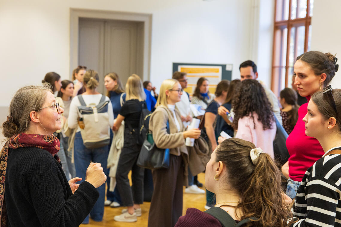 viele Personen stehen in einem Saal und unterhalten sich in kleinen Gruppen