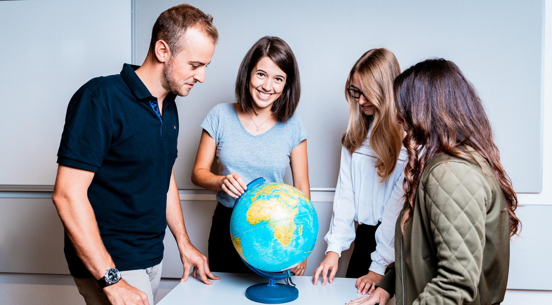 Studierende betrachten einen Globus