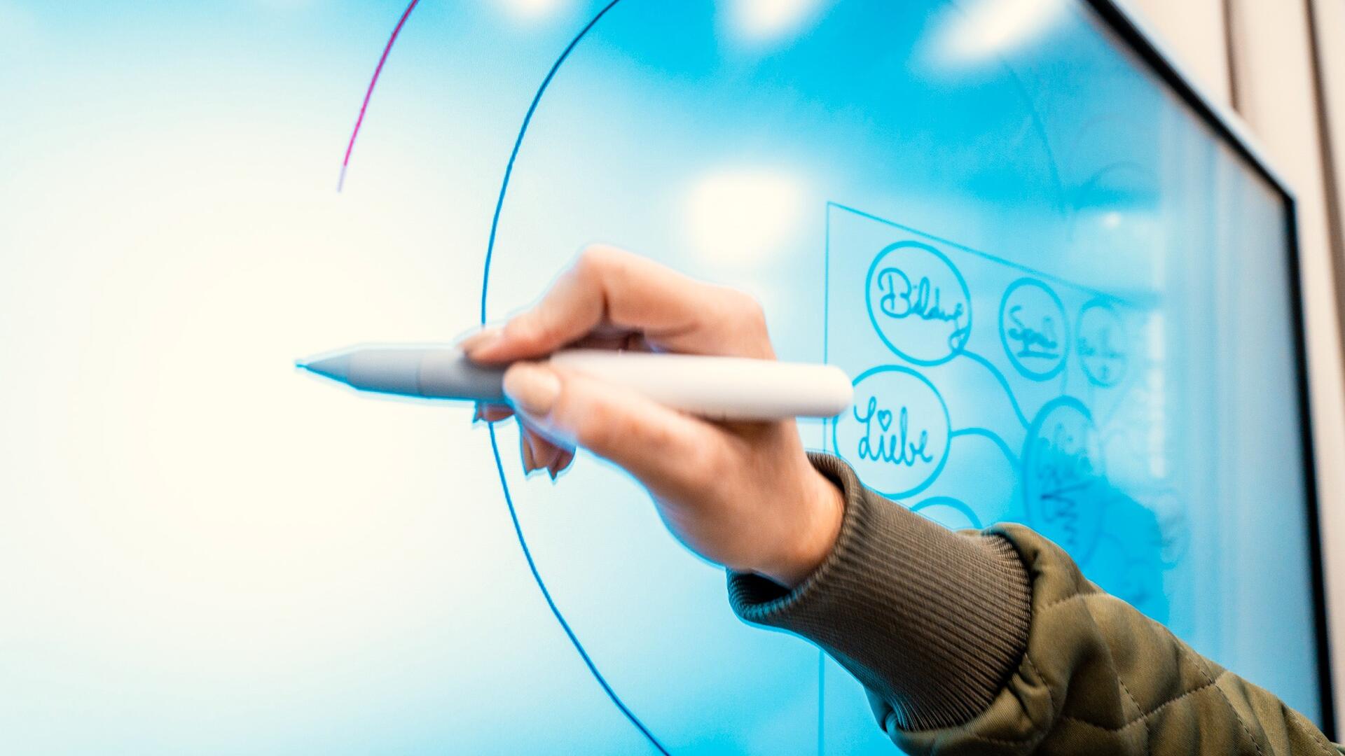 Hand mit Stift auf einer elektronischen Tafel schreibend