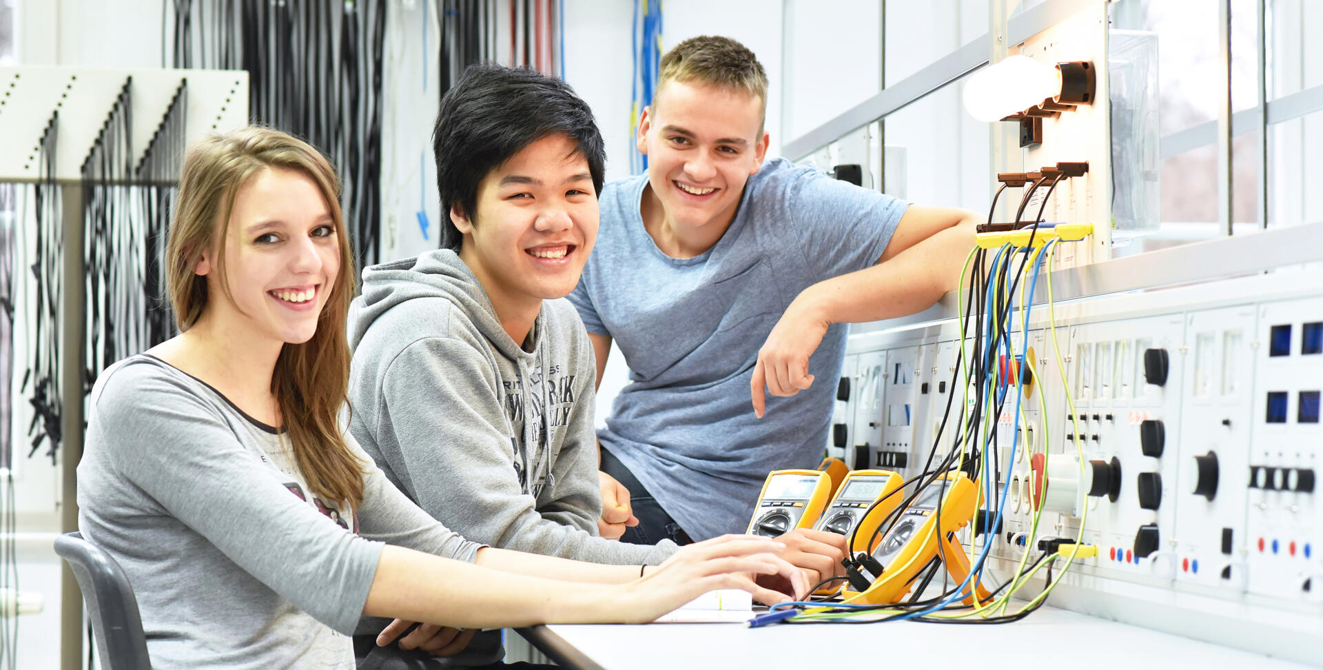 Schüler und Schülerin sitzen vor einem Steuerungsboard